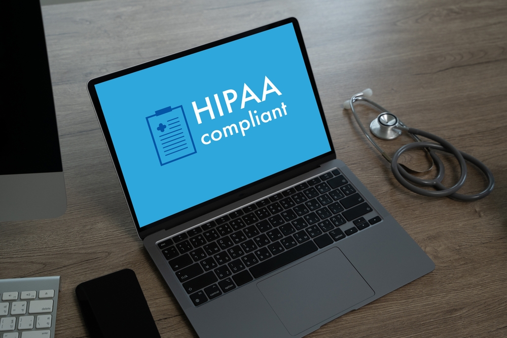 A laptop with the word HIPAA on it. A stethoscope is next to the laptop